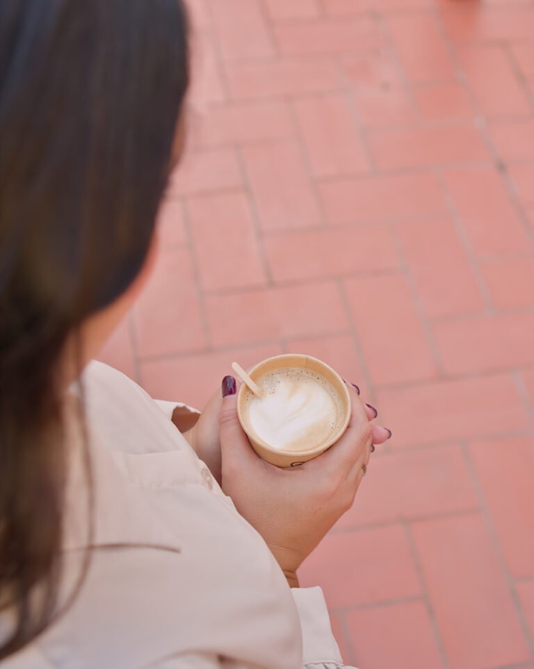 Manos sosteniendo una taza de café en un momento de pausa y autocuidado emocional.