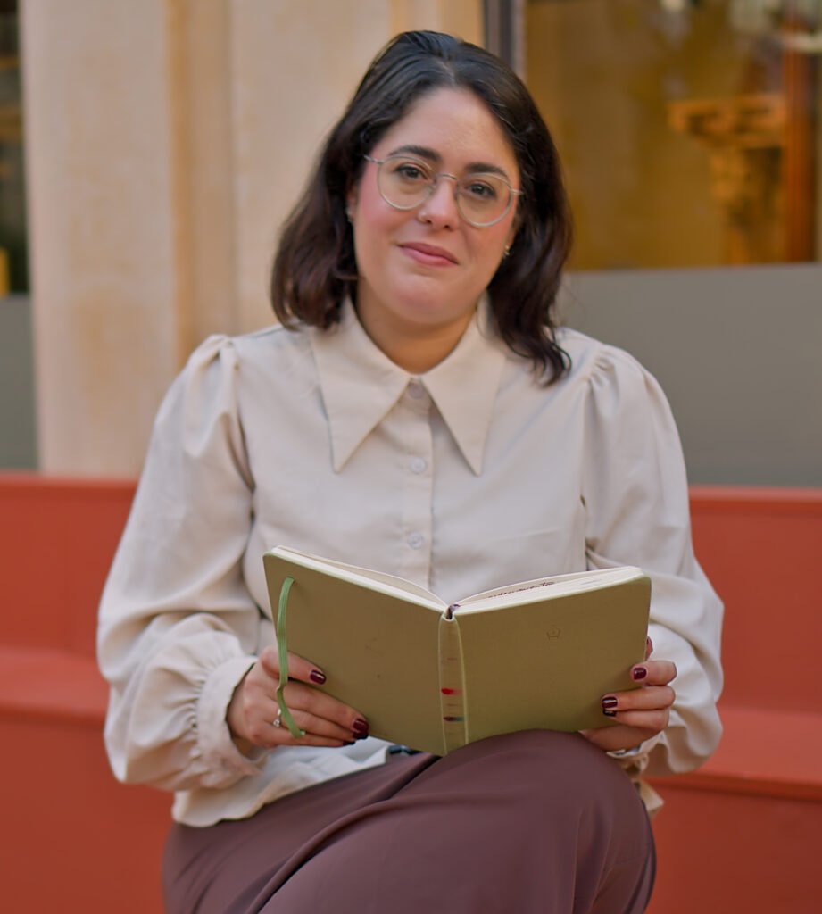 Isa Navarro, coach especializada en alta sensibilidad y bienestar emocional, sosteniendo un cuaderno en un momento de reflexión.